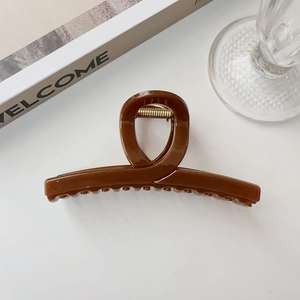 Dettaglio di un grande fermaglio per capelli in acrilico marrone scuro con molla dorata