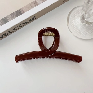 Dettaglio di un fermaglio per capelli marrone caramello lucido con molla dorata