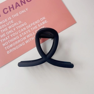 Détail d'une pince à cheveux noire mate avec lignes croisées sur carte rose
