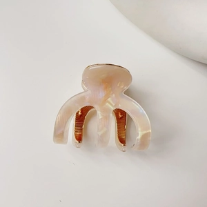 Close-up of small acetate hair claw clip with iridescent pearly white finish and gold hinge