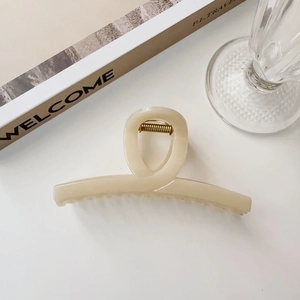 Dettaglio della grande pinza per capelli beige crema con robusta molla in metallo dorato