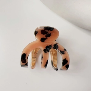 Detail of tortoiseshell acetate hair claw with high-shine gold-tone metal teeth