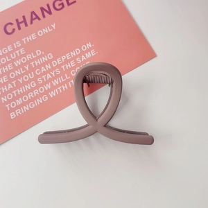 Détail d'une pince à cheveux mate gris-violet avec design croisé pour un style épuré