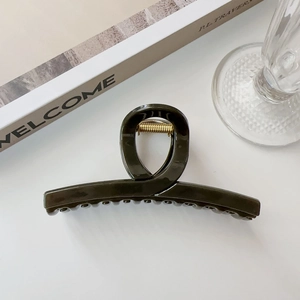 Vista dettagliata di una grande clip per capelli verde scuro con finitura in resina lucida