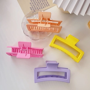 Flat lay of four 13cm matte square hair claw clips in orange, pink, yellow, and purple