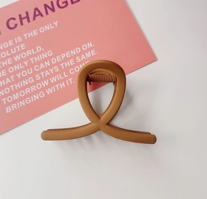 Détail de la pince à cheveux mate caramel avec design croisé pour le coiffage quotidien