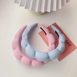 Detailed close-up of pink and blue puffy sponge headbands with soft velvet texture