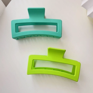 Detail view of two large matte rectangular shark hair clips in mint and neon green colors