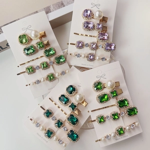 Close-up of emerald and pearl hairpin sets on display cards with vintage metal finish