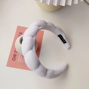 Detail shot of a white padded sponge headband with soft plush fabric and handmade label