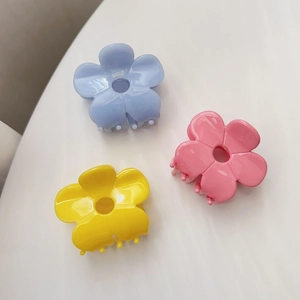 Close-up of candy-colored acetate flower hair claws in blue, pink, and yellow