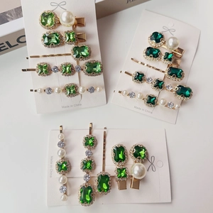 Elegant emerald crystal and pearl hair clip set with gold metal finish on white background