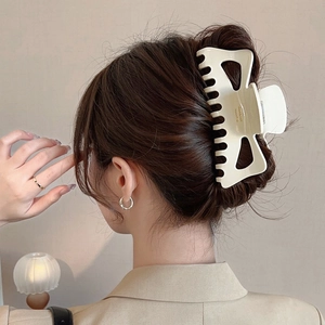 Détail d'une pince à cheveux crème en acétate sur cheveux épais pour un style français