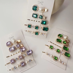 Flat lay macro of vintage emerald rhinestone hair clips with pearls on display card