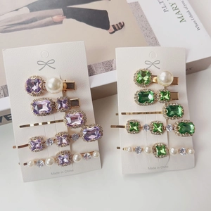 Detail of vintage emerald rhinestone and pearl hair clip set with gold alloy base
