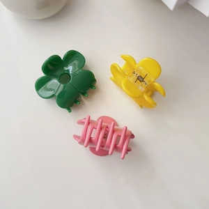 Detailed view of acetic acid flower hair claws in green, yellow, and pink with metal spring