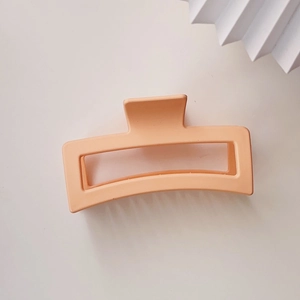 Close-up of a 13cm matte coral orange rectangular shark hair claw clip for thick hair