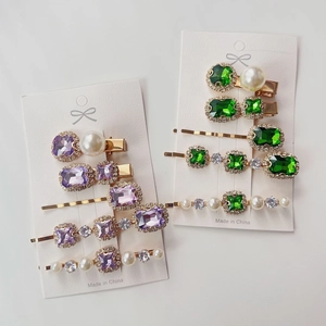 Detail of emerald and purple rhinestone hair clips with pearls on display card