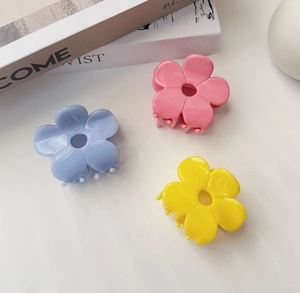 Detail view of acetate flower hair claws in pink, light blue, and bright yellow colors