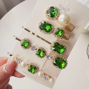 Detail of four-piece emerald rhinestone hair clip set with pearls on display card