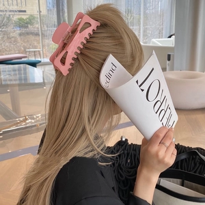 Détail d'une grande pince à cheveux rose mat sur une femme blonde aux cheveux épais