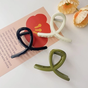 Trois grandes pinces à cheveux en acrylique noir, crème et vert olive au design croisé