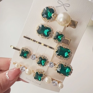 Detail view of 5-piece gold hair clip set with emerald crystals and faux pearls
