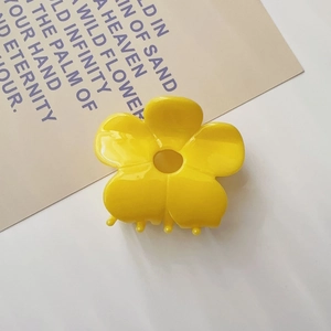 Macro view of bright yellow acetate flower hair claw clip with glossy finish and teeth