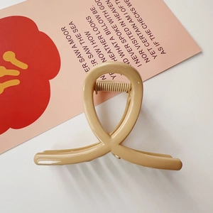 Gros plan sur la pince à cheveux beige mat avec design torsadé sur fond minimaliste