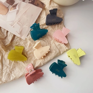 Set of eight colorful carrot-shaped acetate hair claws on a vintage paper background