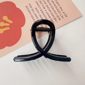 Gros plan d'une pince à cheveux noire avec design croisé élégant sur une carte florale