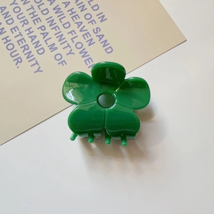 Detail view of a green floral acetate hair claw clip on a clean white background