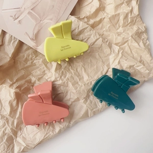 Detailed macro view of carrot-shaped acetate hair clips in yellow, pink and green