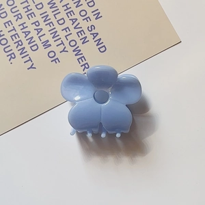 Macro detail of sky blue flower-shaped acetate hair claw clip with smooth resin finish