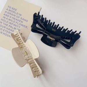 Vue détaillée des pinces à cheveux crème et noires avec des ressorts dorés solides