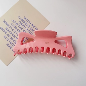 Gros plan d'une grande pince à cheveux rose en acétate avec gravure Barrette La France