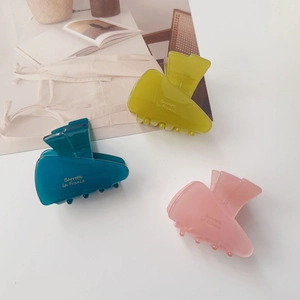 Detailed view of colorful acetate carrot hair clips in green, blue, and pink jelly colors