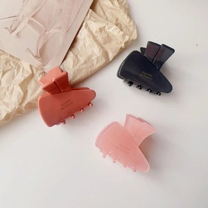 Three-piece acetate carrot hair clips in orange, black, and pink with gold lettering