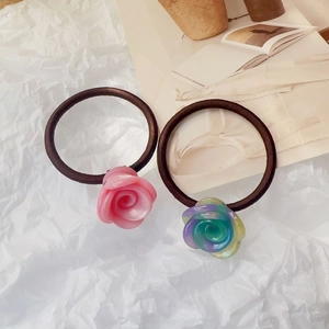 Détail de deux chouchous avec roses en résine et bandes tressées en rose et violet élégant