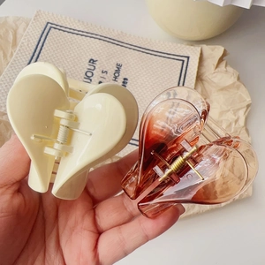 Dettaglio di fermagli per capelli a cuore in resina bianco crema e sfumato ambra