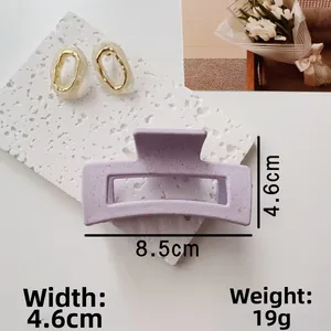 Detail shot of a matte lavender rectangular hair claw clip with cream resin earrings