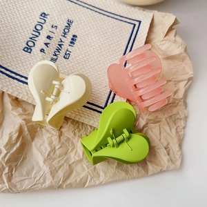 Dettaglio dei fermagli per capelli a forma di cuore in giallo, rosa opaco e verde