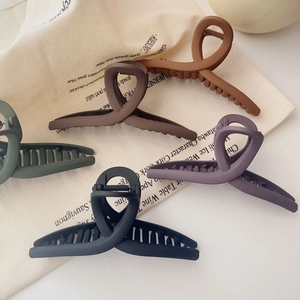 Pinces à cheveux mates au design croisé en cinq couleurs sombres sur fond crème