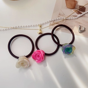 Détail de trois chouchous avec fleurs de rose 3D en blanc perle, rose et dégradé