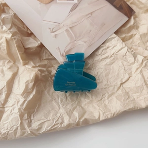 Detailed view of a dark teal acetate hair claw with gold Barrette la France lettering