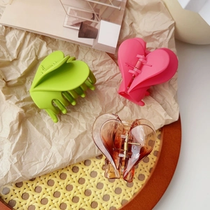 Dettaglio delle mollette a forma di cuore in verde, magenta e marrone caffè