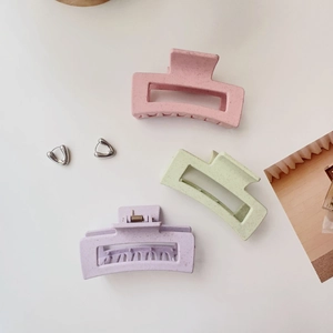 Close-up of matte rectangular hair claws in pink green and purple on a white background