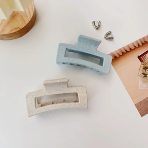 Detail of matte rectangular hair claw clips in blue and beige with speckled texture