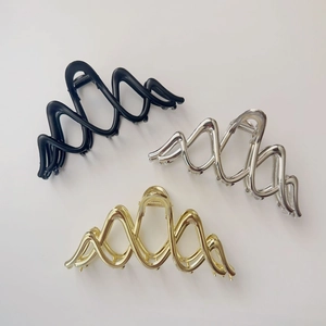 Detailed top view of wave-shaped metal hair claws in matte black, silver, and gold finishes