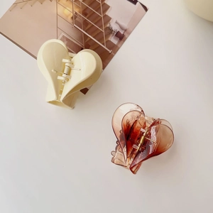 Dettaglio di mollette per capelli a forma di cuore in crema e resina ambrata